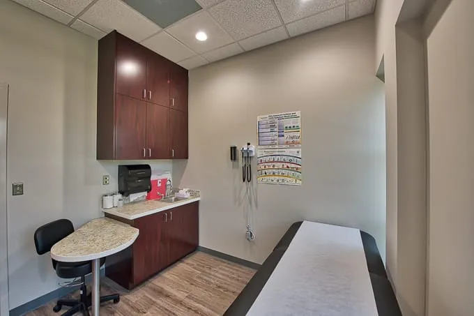 Exam room with exam table, wall-mounted diagnostic instruments and cabinets at Allergy & Asthma Physicians of Commerce Township